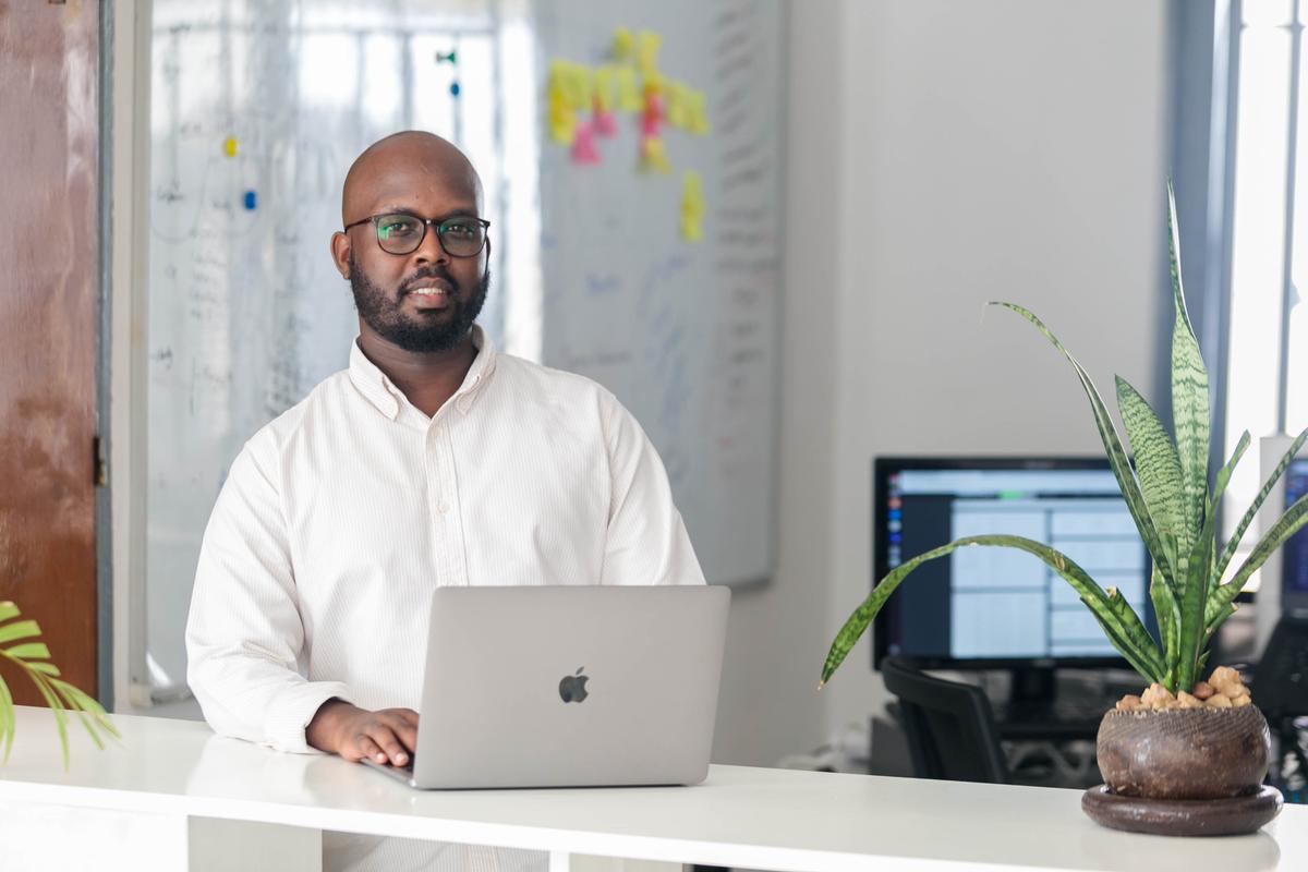 A data engineer from Awesomity Lab at a laptop in the Kigali office, with a whiteboard behind him.